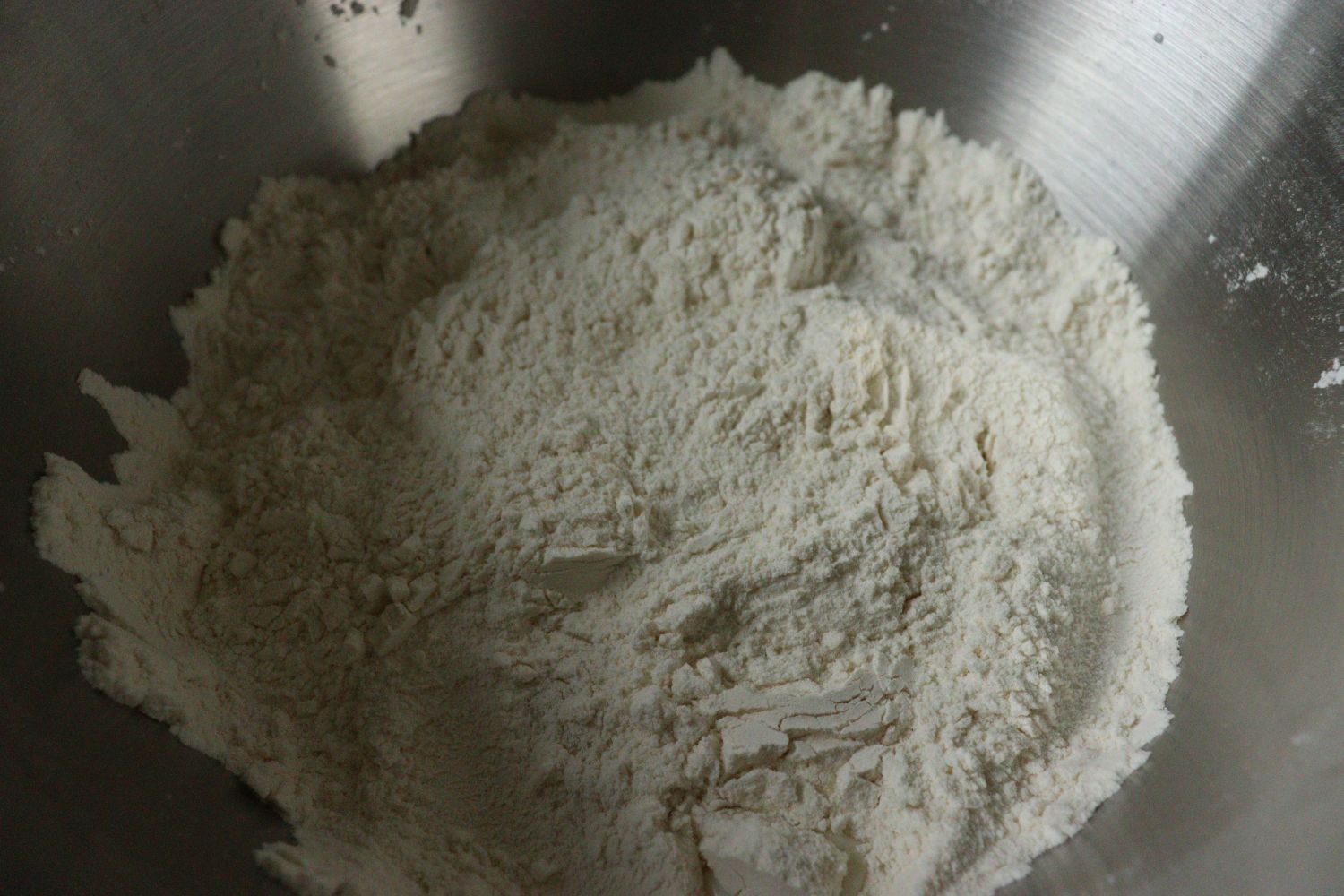 Flour mixed with salt, added yeast, sugar and milk in the middle, and covered with flour from the sides, for Yeast Dough - Hefeteig. 