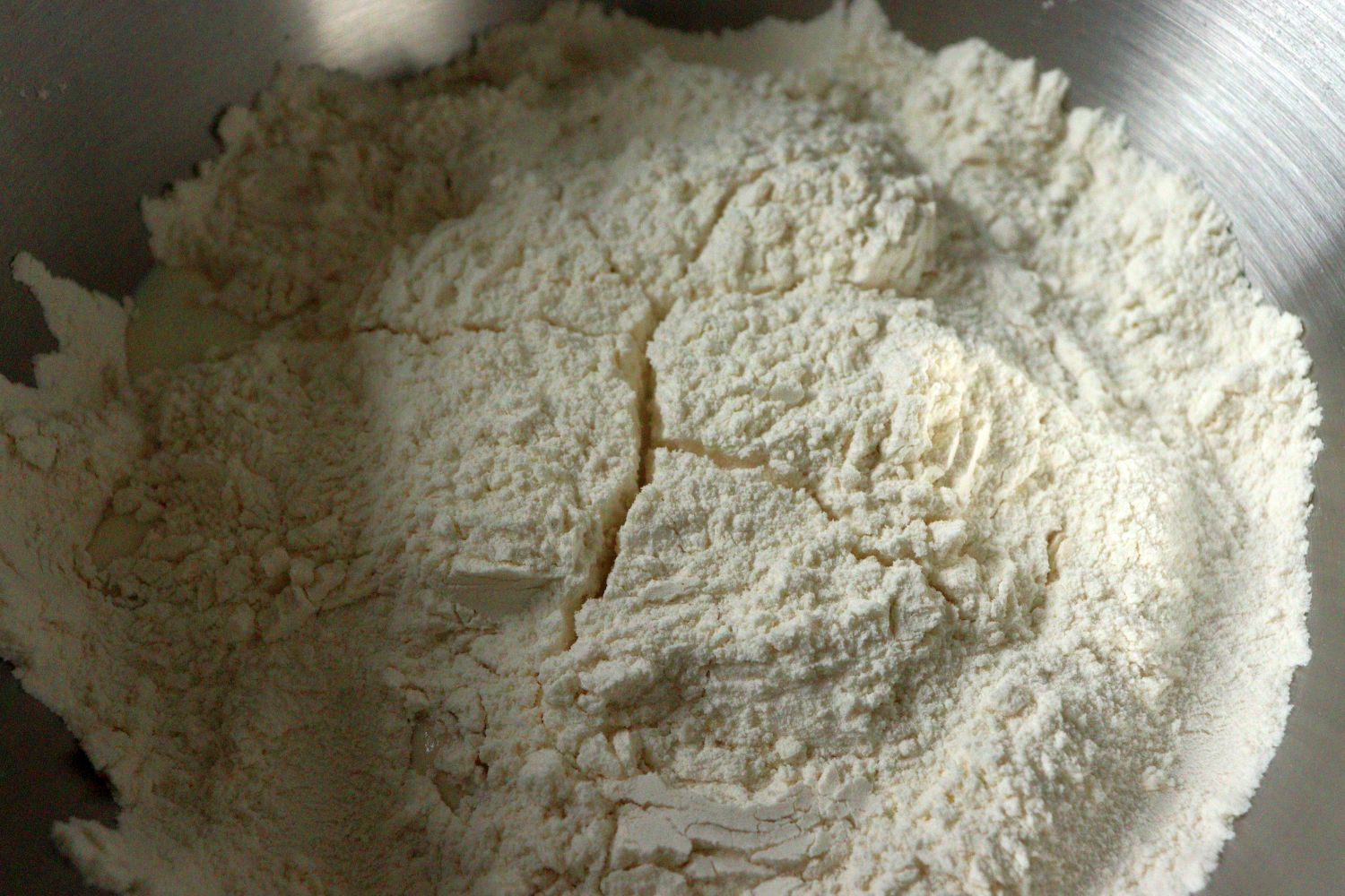 Flour mixed with salt, added yeast, sugar and milk in the middle, and covered with flour from the sides, for Yeast Dough - Hefeteig. - Proofed yeast dough. 