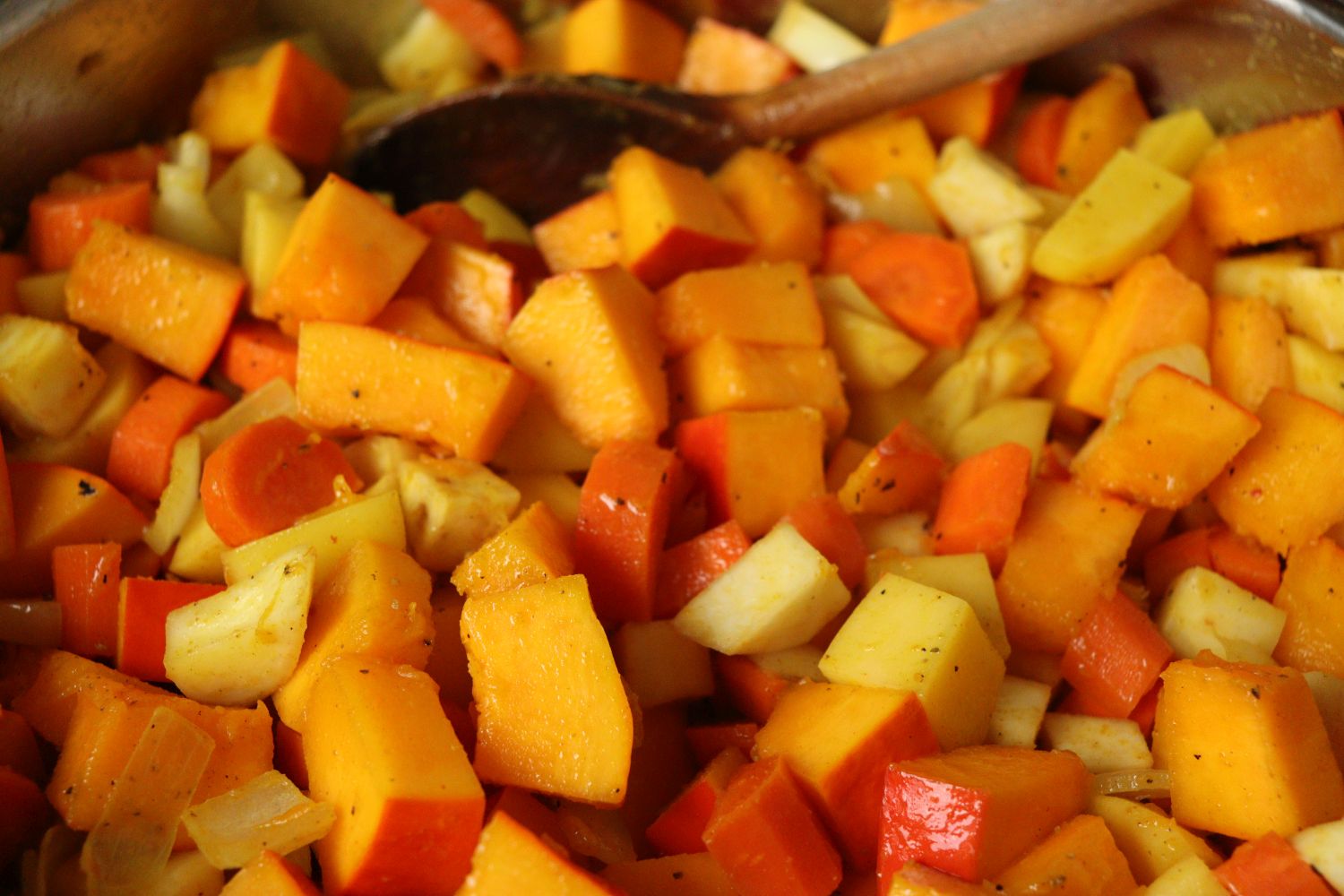Fried pumpkin, celery root, carrots, potatoes and onion cubes in a pan for making pumpkin soup