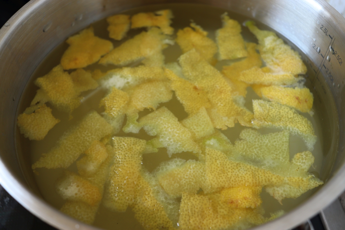 Water, sugar, lemon juice and lemon peel is boiled in a pot for making syrup. 
