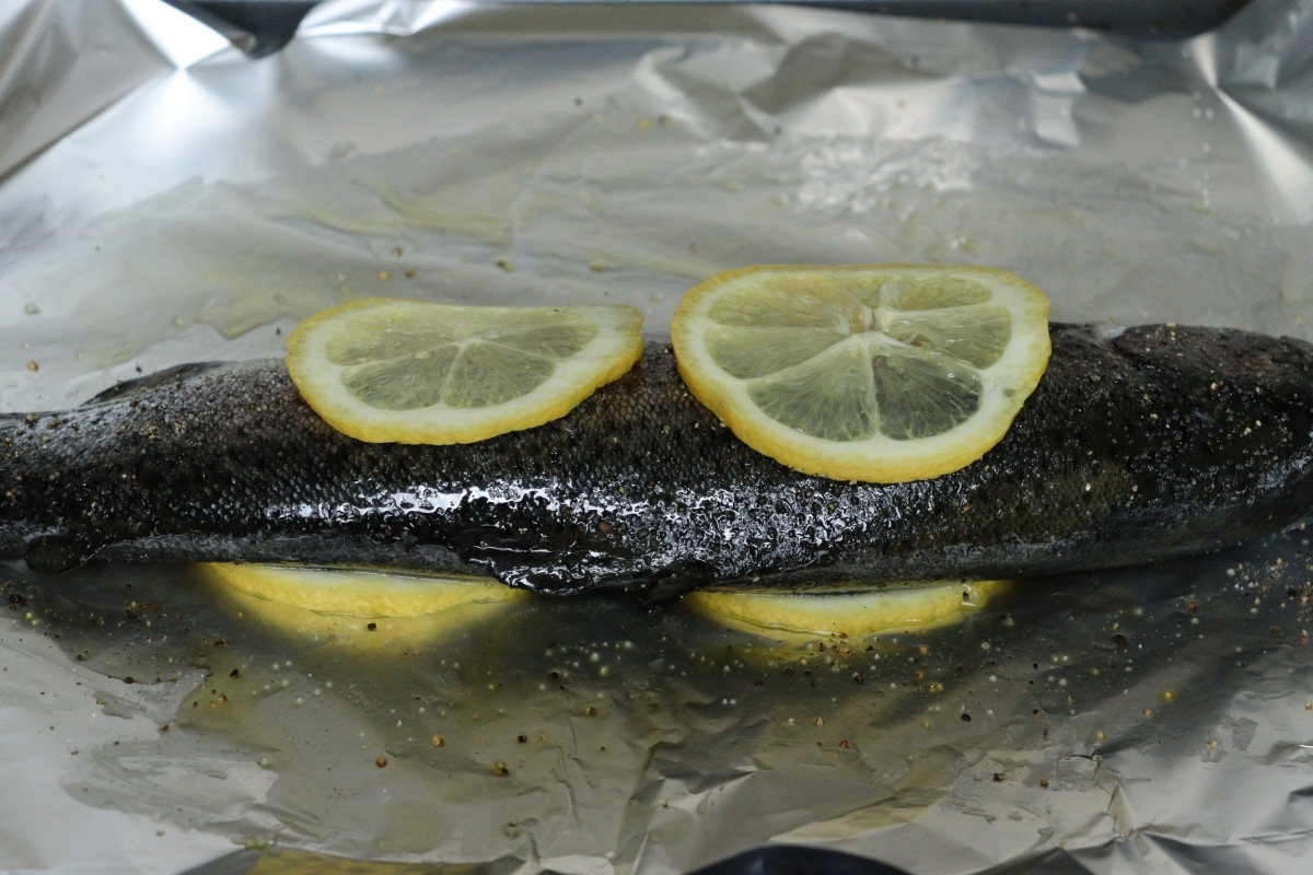 Trout coated with olive oil, salt, and pepper, stuffed with sage leaves and covered with lemon slices