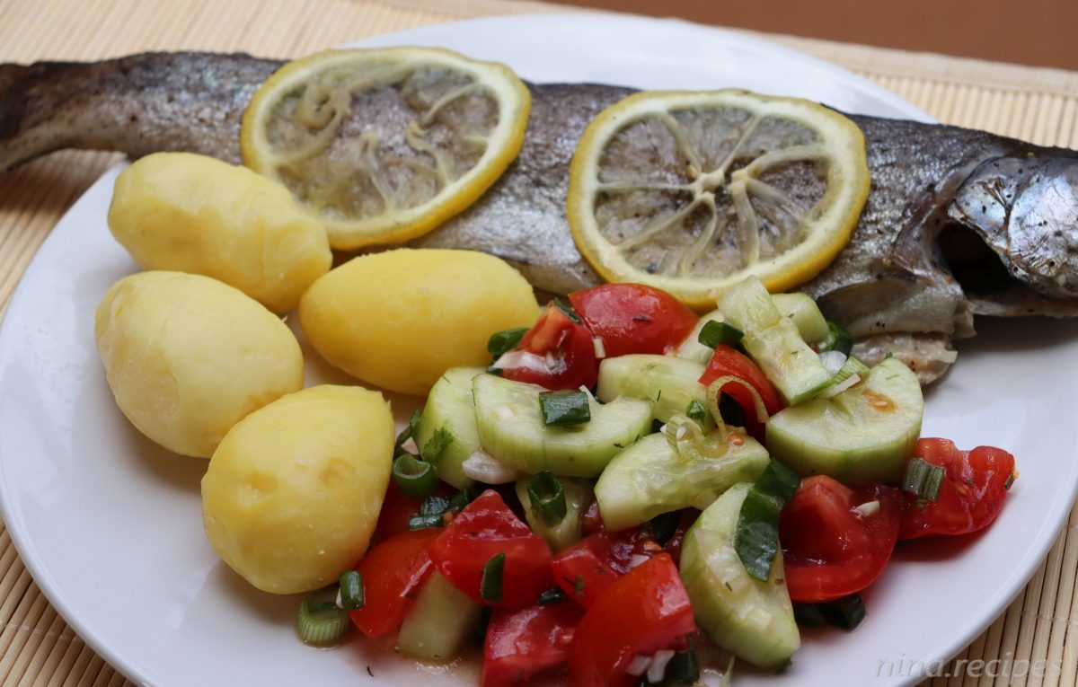 Baked trout in foil, served with boiled potatoes and tomatoes and cucumber salad