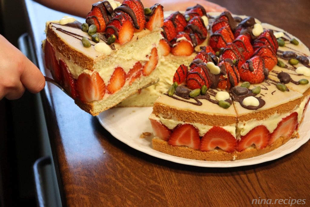 Section of a Fraisier cake (Fraisier Torte), french strawberry layered cake with a butter custard vanilla cream, many strawberries, a marzipan top and chocolate decor