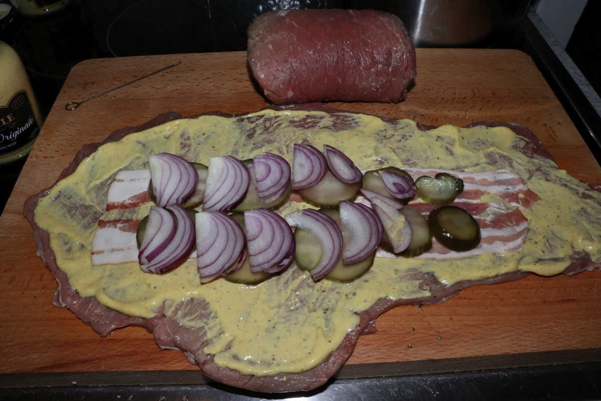 Beef slice covered in mustard, with bacon stripes, pickled cucumbers and onions, for Rinderrouladen